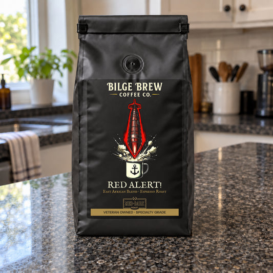 A black coffee bag labeled 'Bilge Brew Coffee Co. Red Alert!' stands on a granite kitchen countertop with a blurred kitchen background.