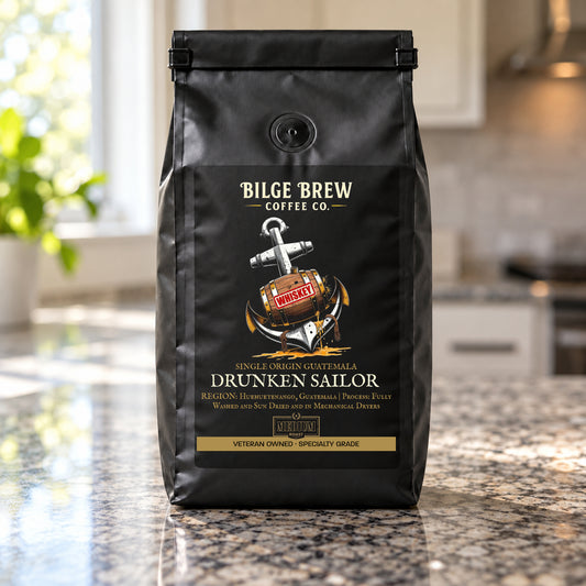A black coffee bag from Bilge Brew Coffee Co. standing on a granite counter in a kitchen setting.