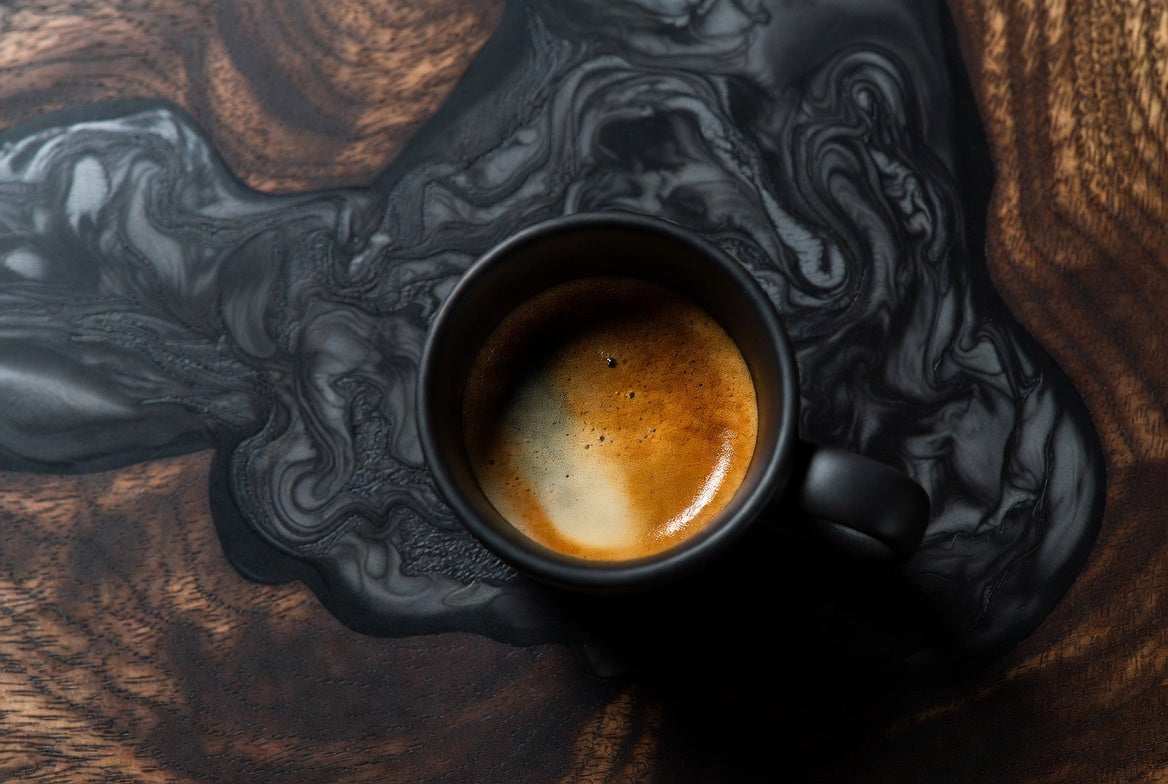 dark, moody, luxurious feel. dark walnut with black epoxy inlay setting. of an artisan glass of espresso, full body crema