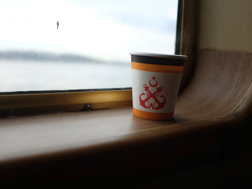 Cup with symbol on windowsill by water