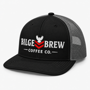 A black and gray trucker hat with a black front panel, white embroidered 'BILGE BREW COFFEE CO.' text, and a red chevron logo, shown on a light gray background.