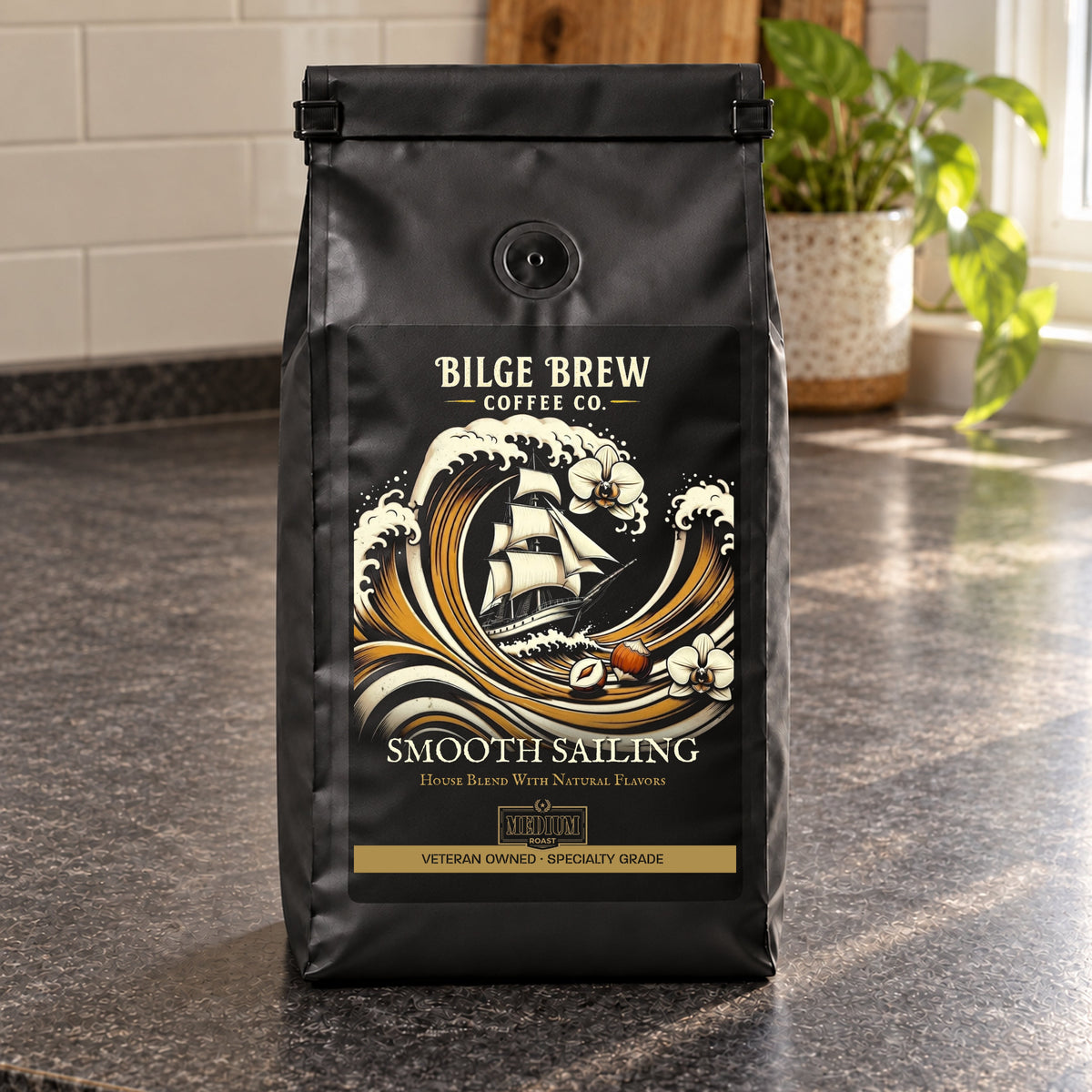 A black bag of Bilge Brew Coffee Co. 'Smooth Sailing' house blend coffee sits on a dark granite countertop in a kitchen setting with a tiled backsplash and a potted plant in the background.