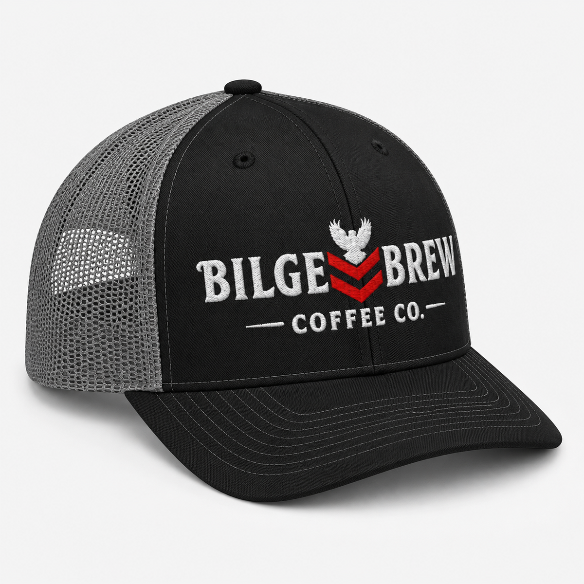 A black trucker hat with a gray mesh back, featuring a white embroidered eagle logo and the text 'BILGE BREW COFFEE CO.' with a red chevron accent on the front panel.