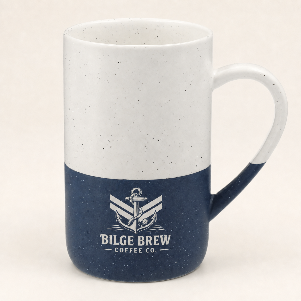 A ceramic coffee mug with a two-tone design, featuring a white upper half with subtle speckles and a navy blue lower half. The mug is printed with a white anchor logo and the text 'BILGE BREW COFFEE CO.