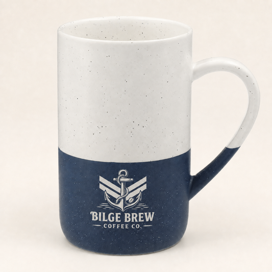 A ceramic coffee mug with a two-tone design, featuring a white upper half with subtle speckles and a navy blue lower half. The mug is printed with a white anchor logo and the text 'BILGE BREW COFFEE CO.