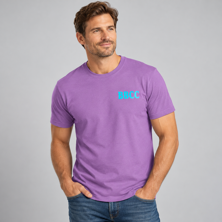 A man wearing a purple short-sleeve crewneck t-shirt with the letters 'BBCC' printed in light blue on the left chest, paired with blue jeans, against a solid gray studio background.
