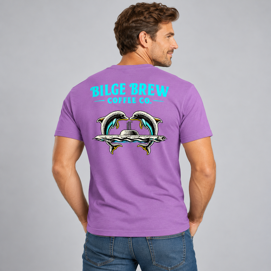 A man wearing a purple t-shirt, viewed from the back. The shirt features a graphic of two dolphins facing each other above a silver submarine, with the text 'BILGE BREW COFFEE CO.