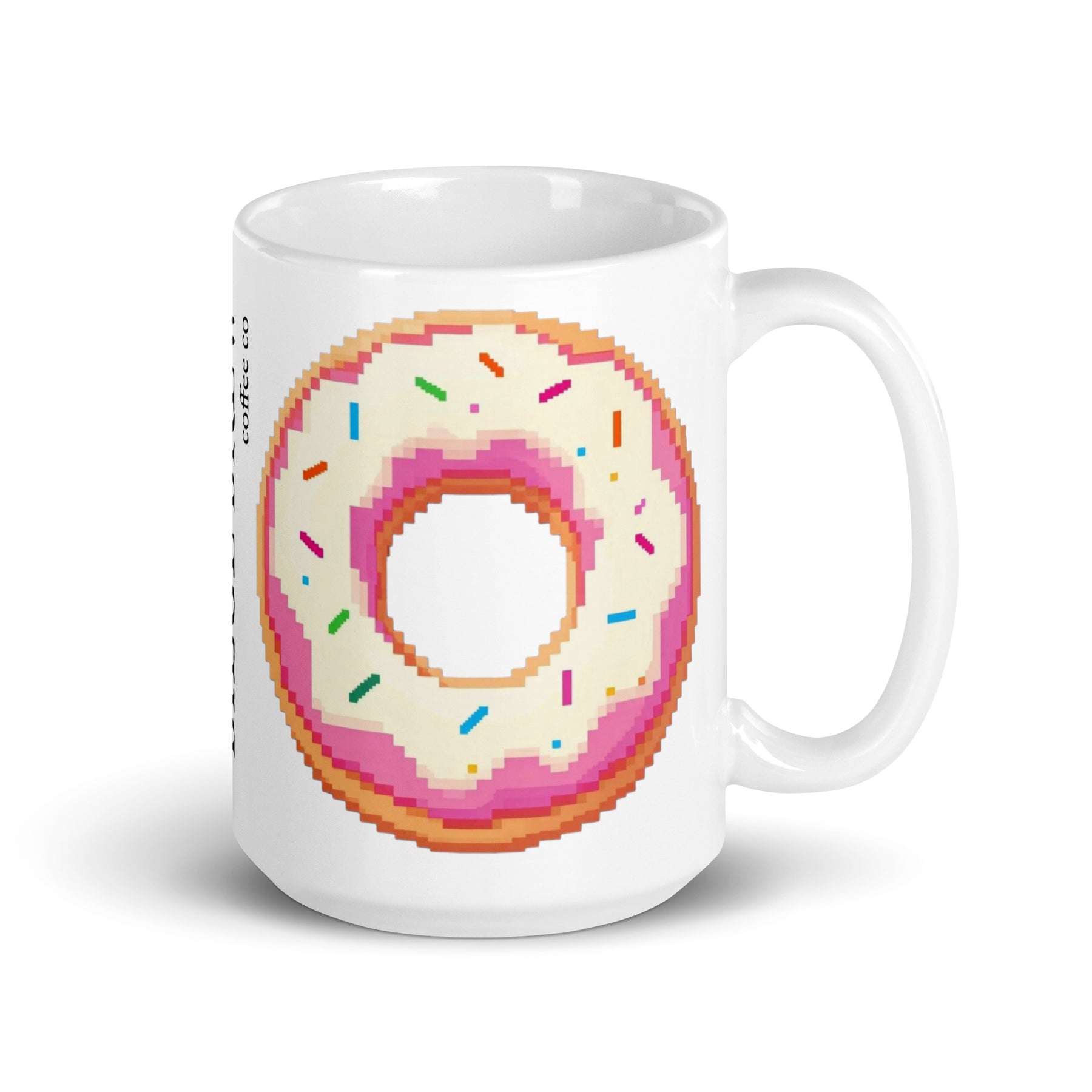 A white ceramic coffee mug featuring a pixel-art style graphic of a donut with pink frosting and colorful sprinkles, shown on a clean white background.