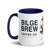 A white ceramic coffee mug with a dark navy blue handle, interior, and printed graphics. The mug features the text 'BILGE BREW COFFEE CO.