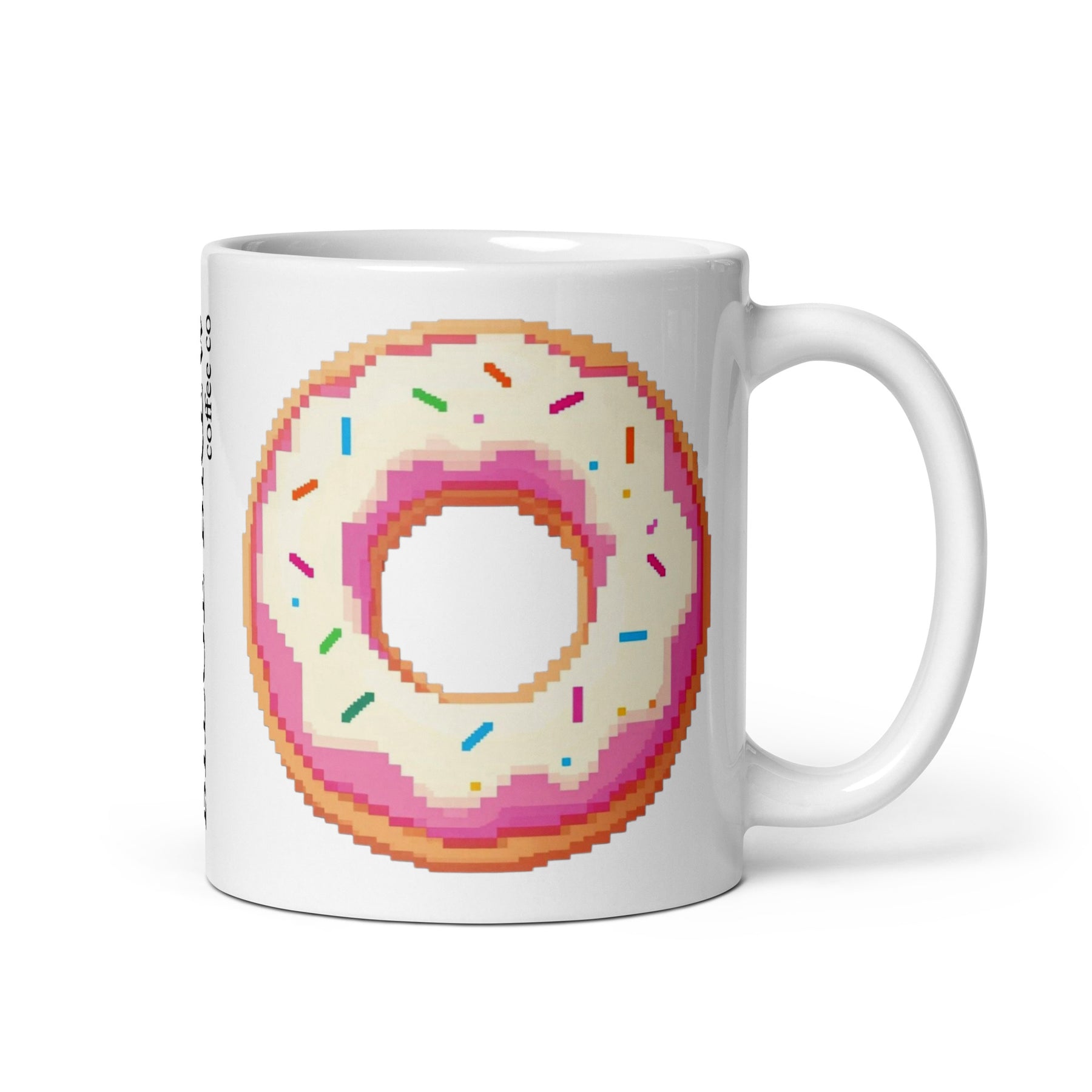 A white ceramic mug featuring a pixel-art style donut graphic with pink frosting, white icing, and multicolored sprinkles, shown on a clean white background.