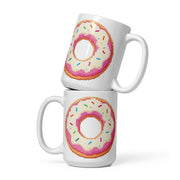 Two stacked white ceramic mugs featuring a pixel-art style donut design with pink frosting, white icing, and multicolored sprinkles on a clean white background.