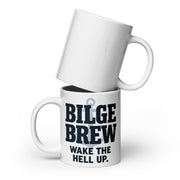 Two white ceramic mugs stacked on a white background. The bottom mug has bold dark navy text reading 'BILGE BREW' and smaller text 'WAKE THE HELL UP.