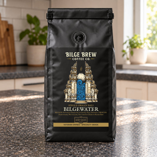A black bag of Bilge Brew Coffee Co. Bilgewater Single Origin Batch coffee stands on a granite countertop in a kitchen setting.