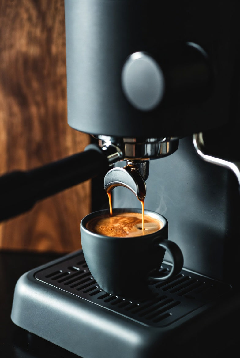 Espresso being brewed into a black cup from a coffee machine.