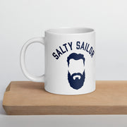 White mug with 'Salty Sailor' design featuring a beard illustration on a wooden surface.