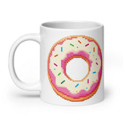 A white ceramic mug featuring a pixel-art style graphic of a donut with pink frosting and colorful sprinkles, shown on a clean white background.